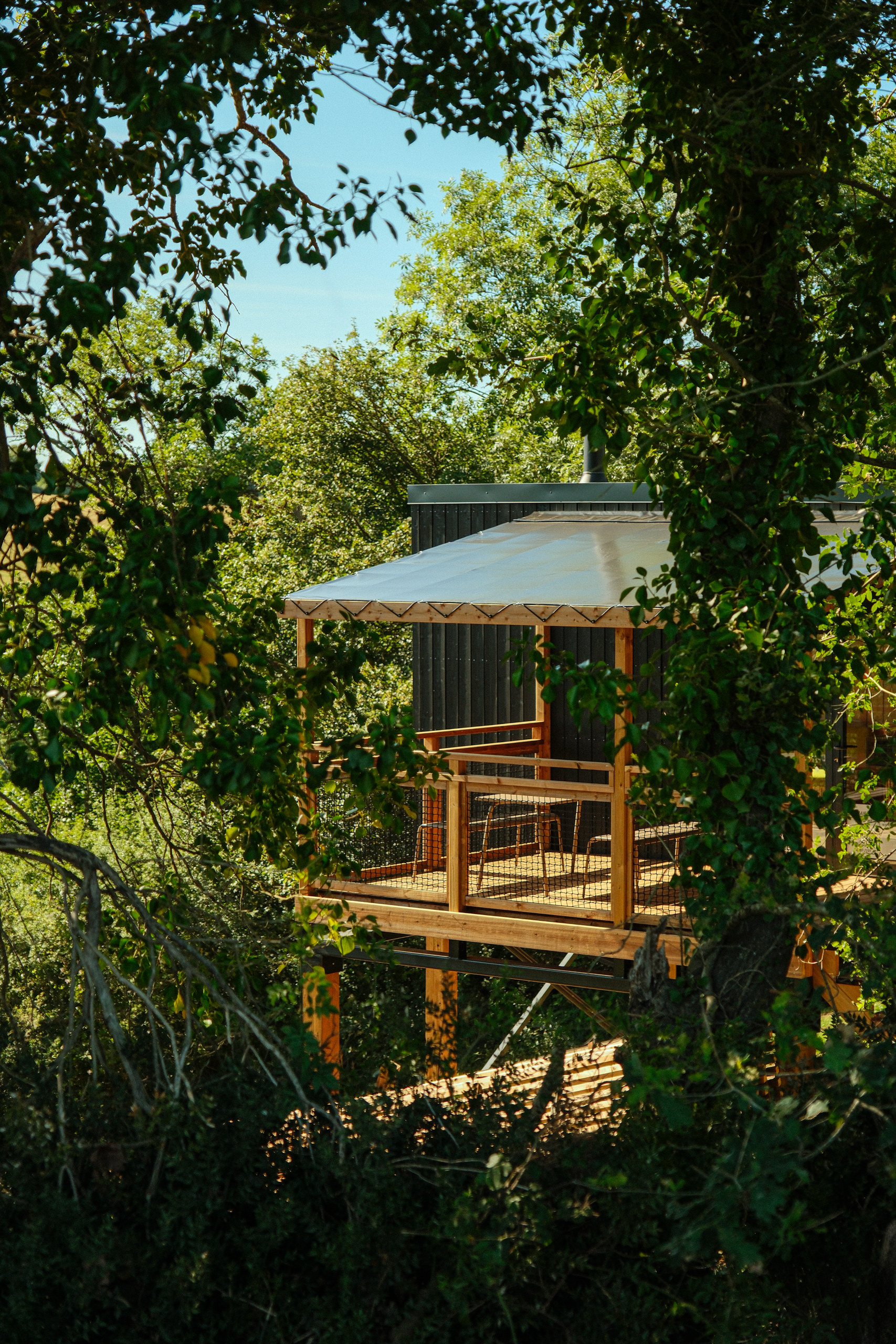 Terrasse extérieure d'une cabane entourée de verdure au Bon Air Club à Saint-Léonard-des-Bois