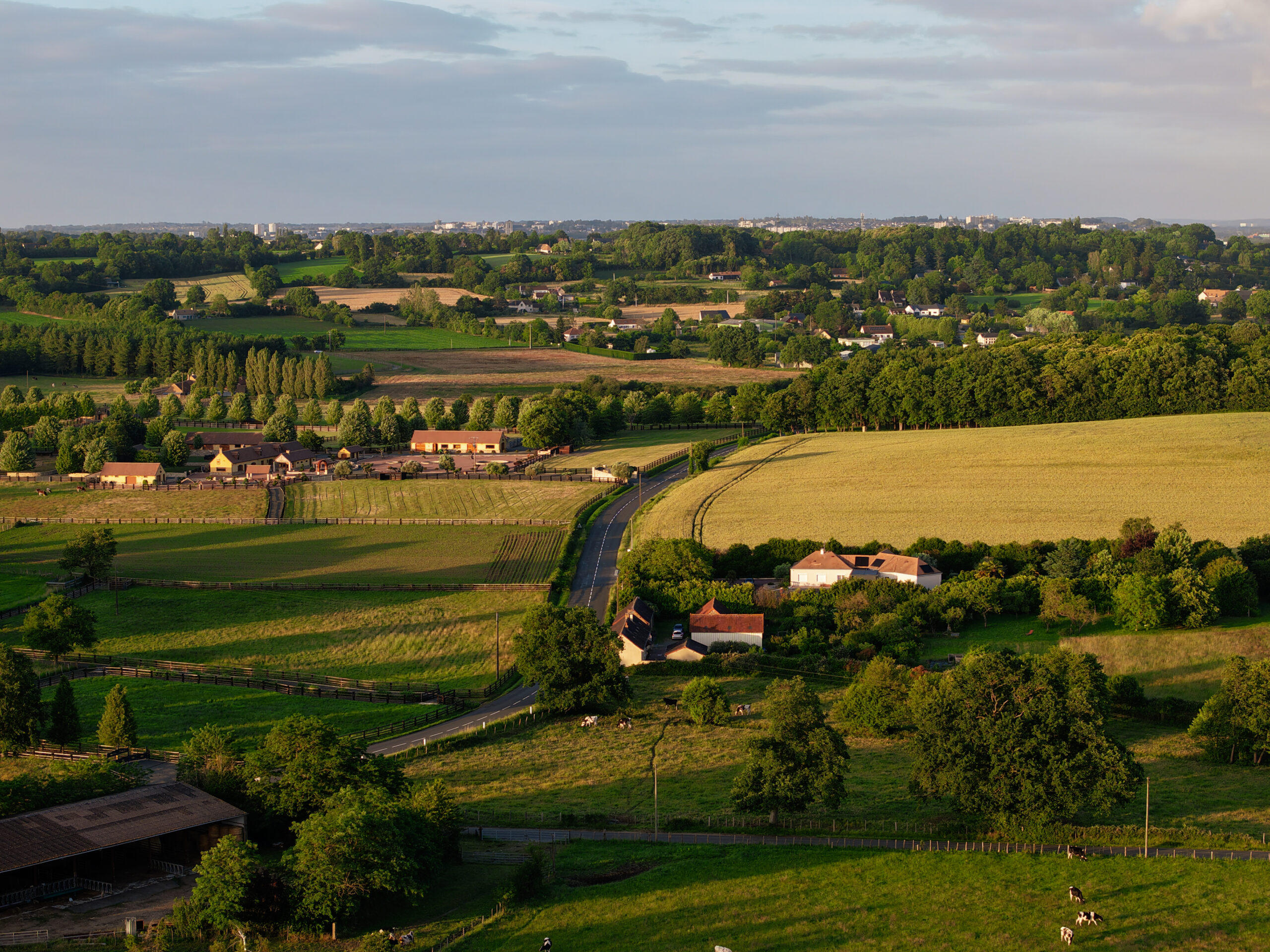 Route de campagne entre champs et ferme, vue aérienne par drone en Sarthe
